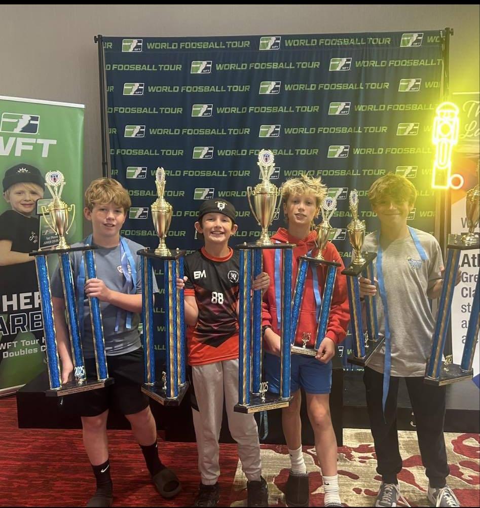 Five young players holding tall championship trophies at the 2025 Great Lakes Classic