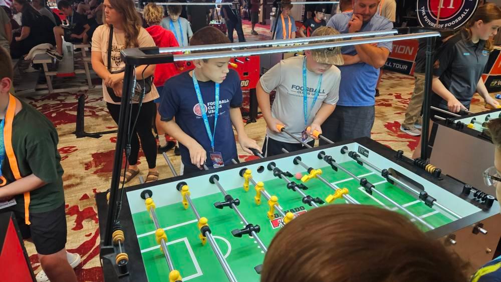 Two students in Foosball Clubs USA shirts playing a match at the 2025 Great Lakes Classic