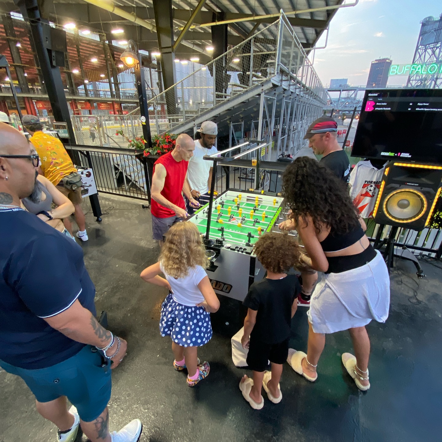 Families and adults of all ages playing foosball at an outdoor community event