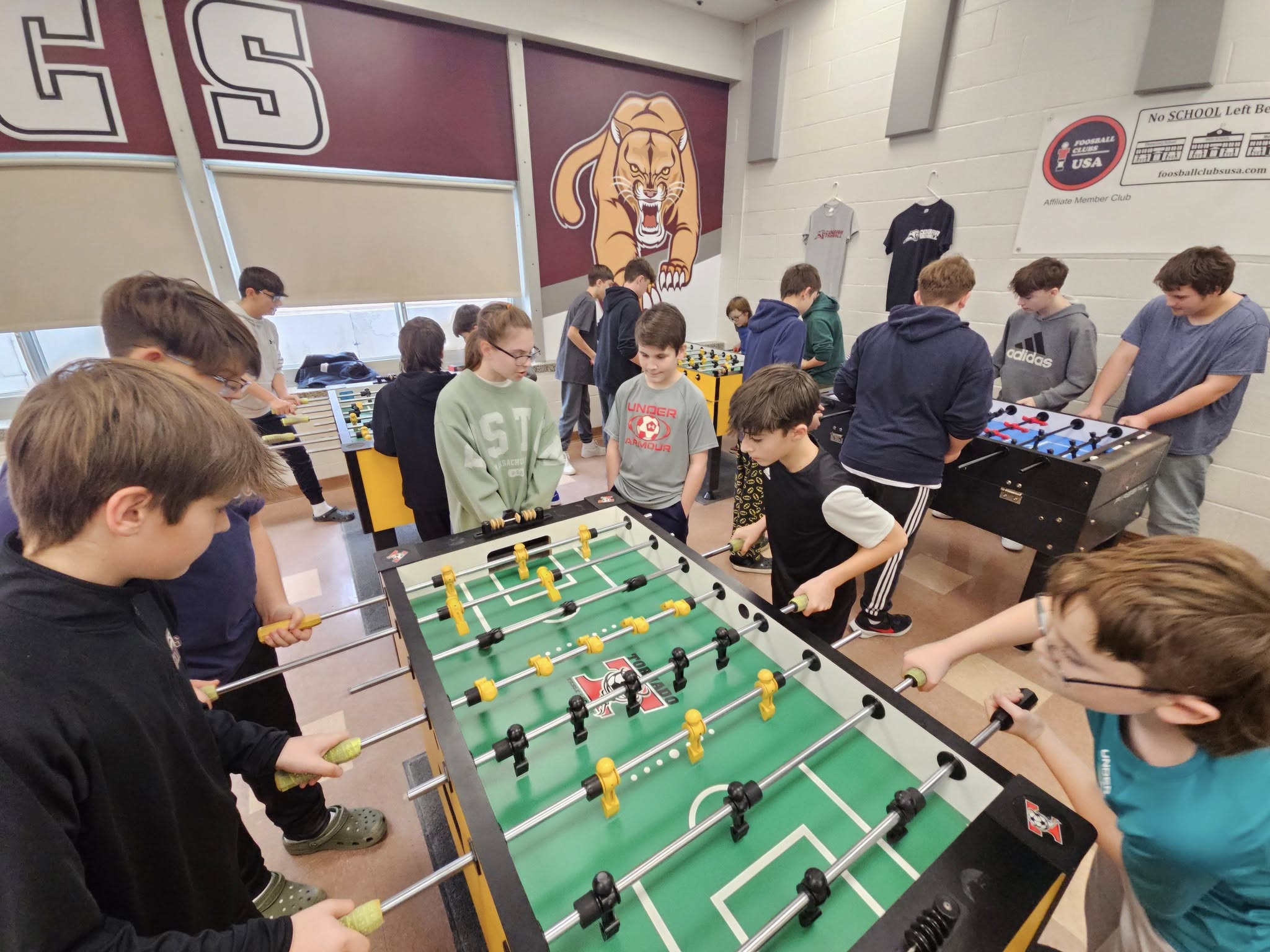 Middle school students playing foosball on three tables at their school club